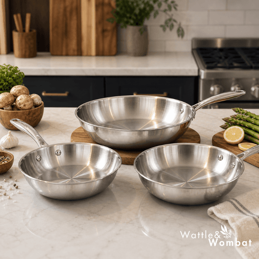 Set of stainless steel frying pans on a kitchen counter with 'Wattle & Wombat' branding.